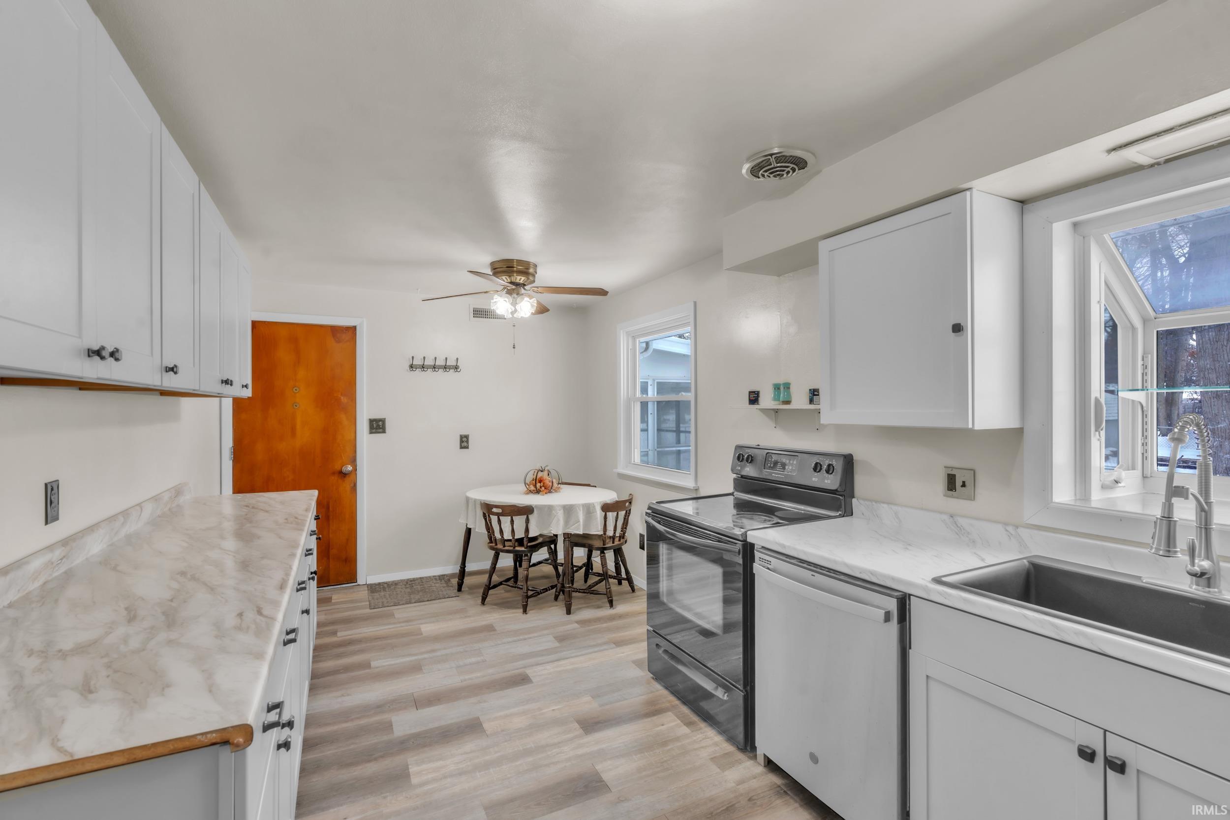 Kitchen with electric range, light countertops, white cabinetry, stainless steel dishwasher, and a ceiling fan