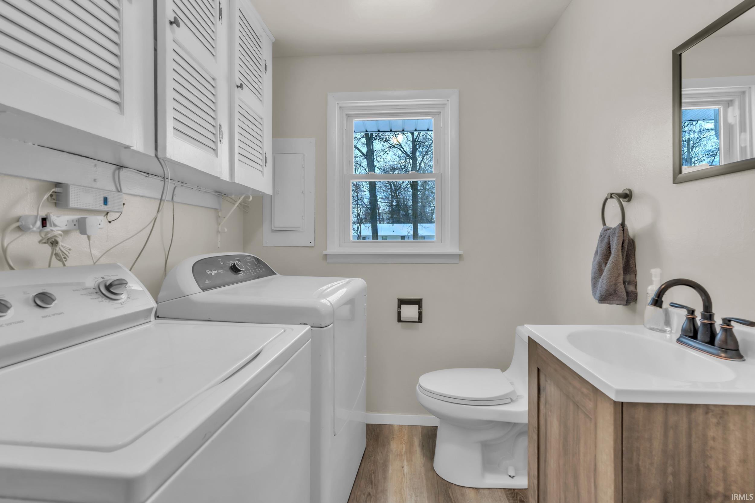 Washroom featuring separate washer and dryer, electric panel, and light wood-style floors