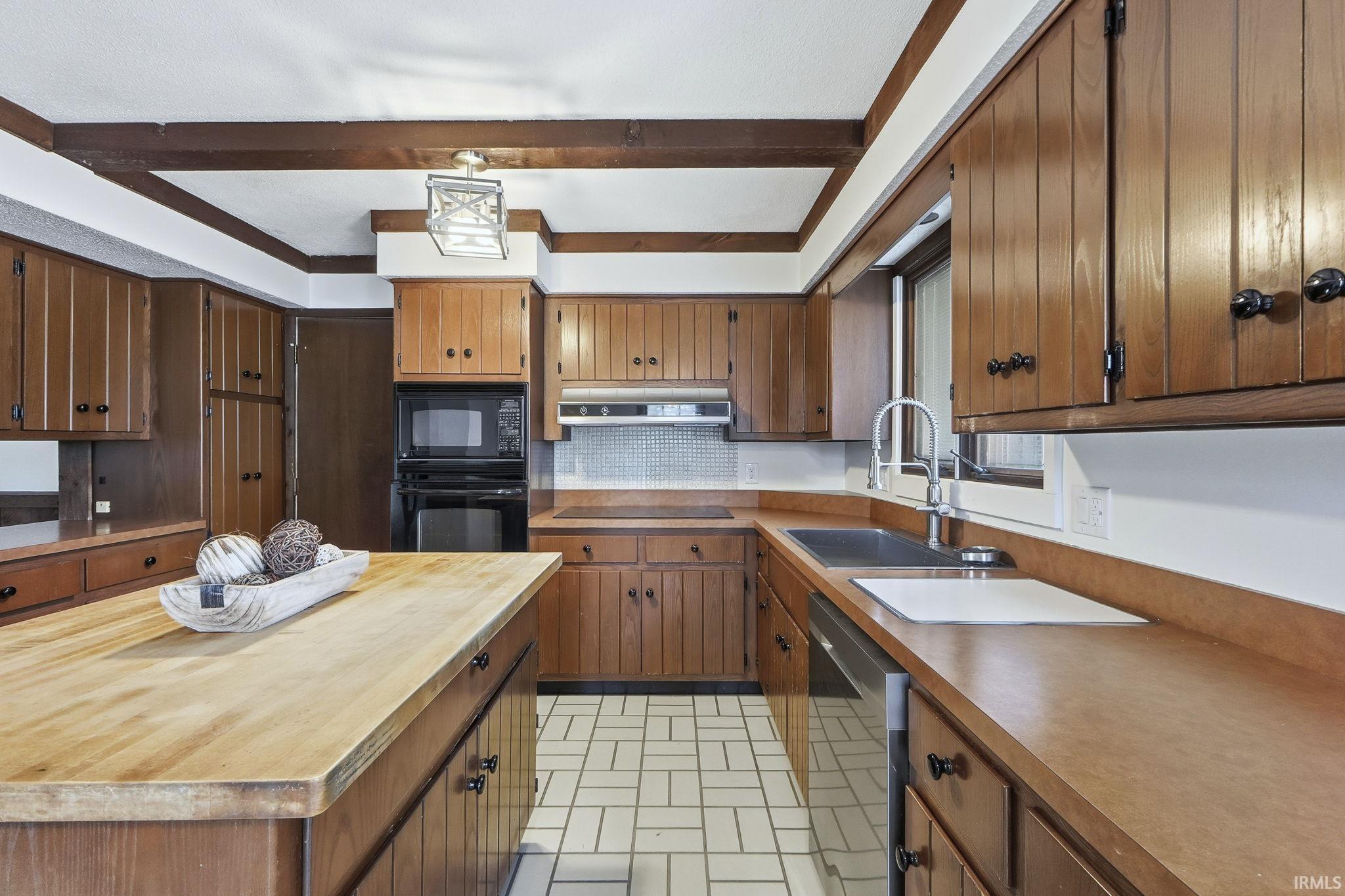 Kitchen featuring wooden counters, black appliances, brick patterned flooring, brown cabinets, and backsplash