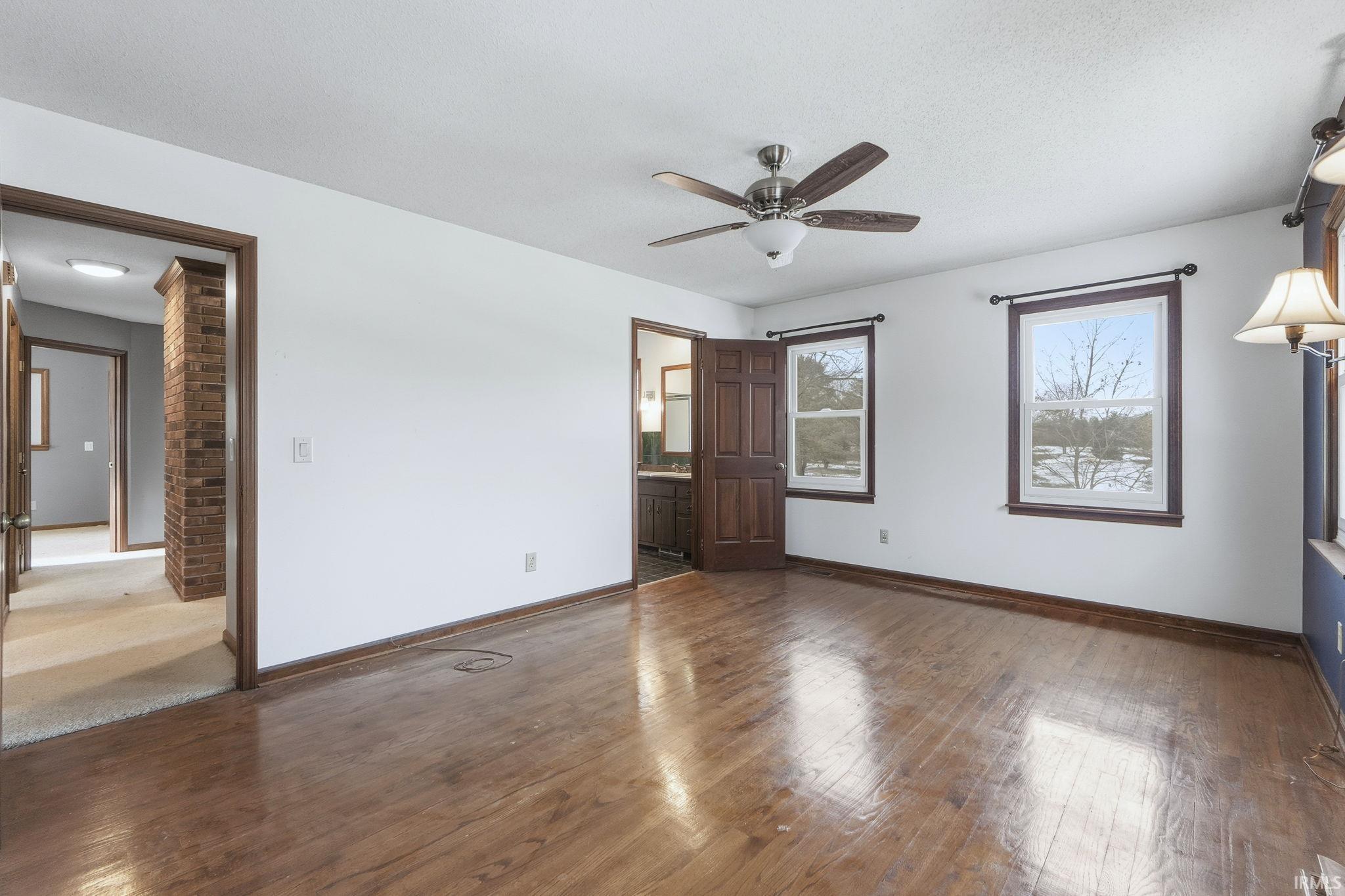 Unfurnished bedroom with hardwood / wood-style floors, ensuite bath, a ceiling fan, and a textured ceiling