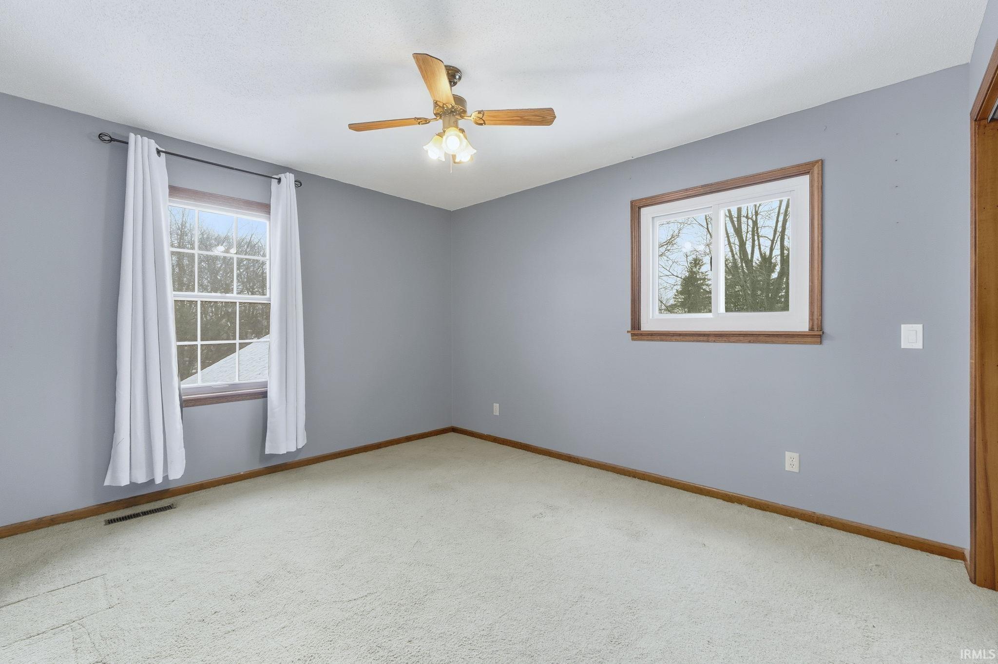 Empty room featuring plenty of natural light, light carpet, and a ceiling fan
