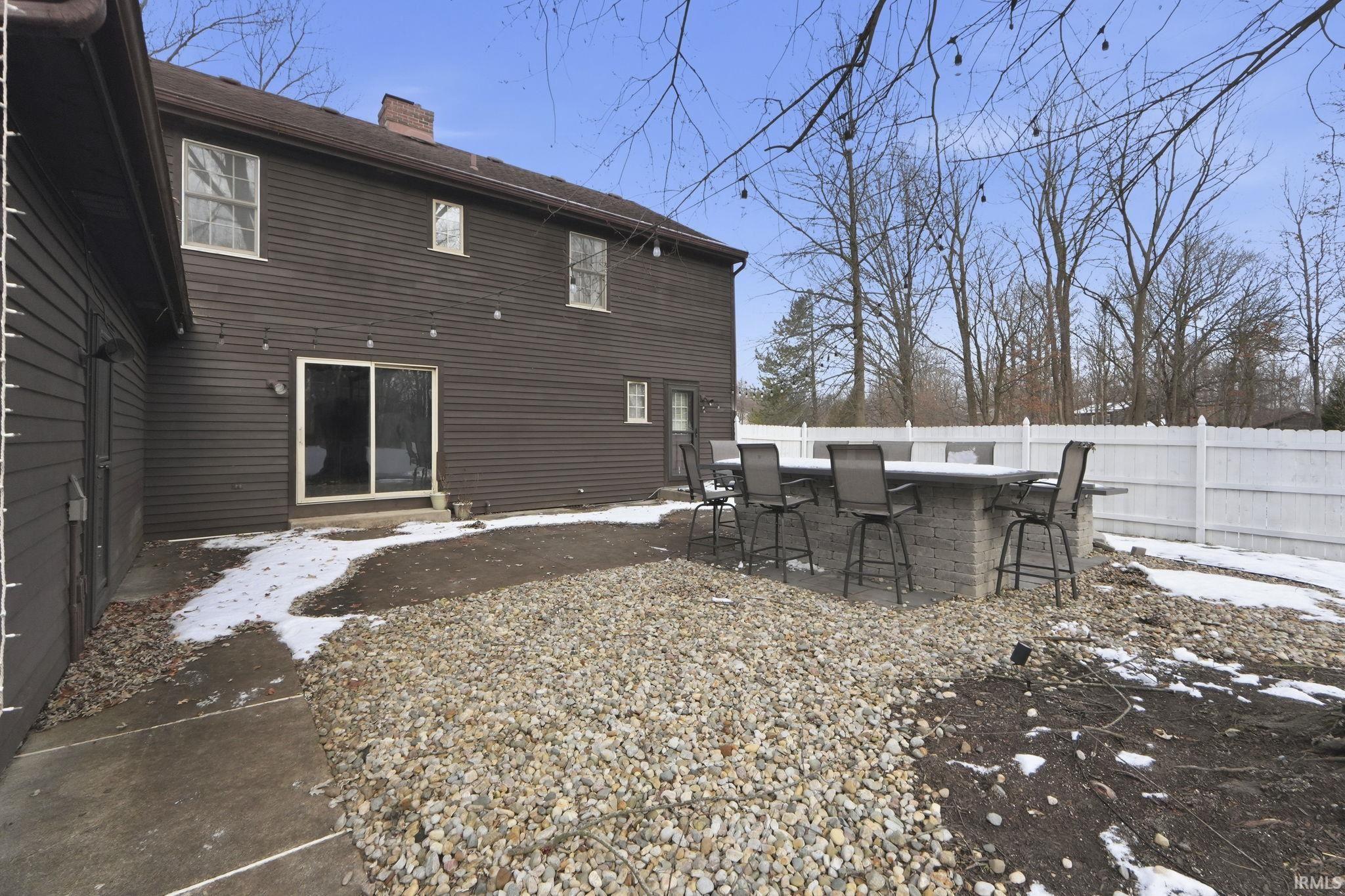 Snow covered property with a patio and a chimney