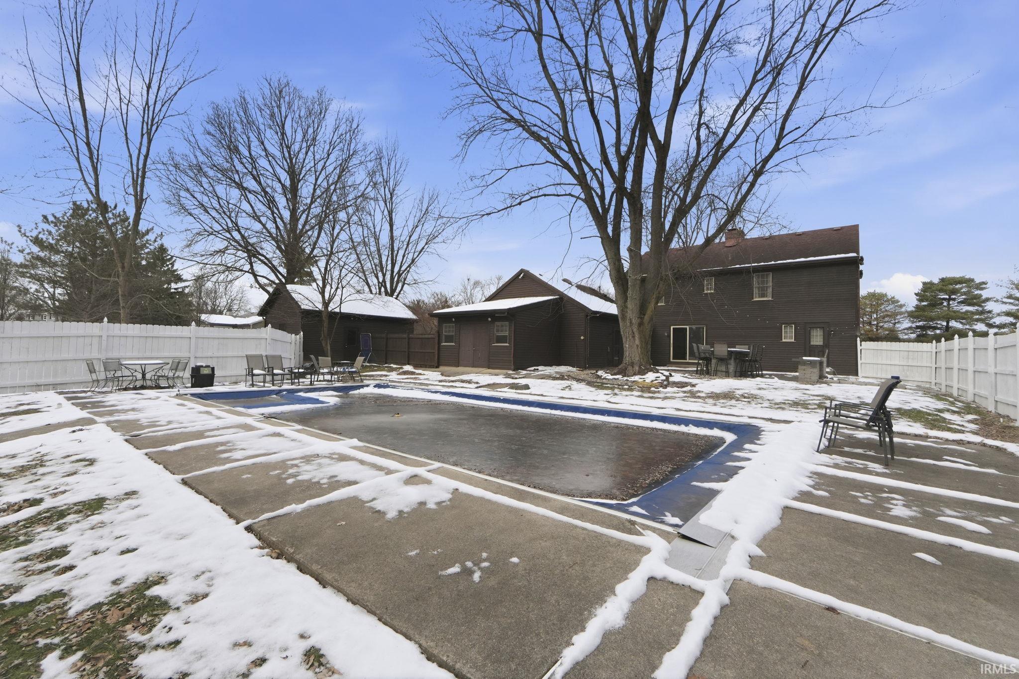 Snow covered pool with a fenced backyard, a patio, and a community pool