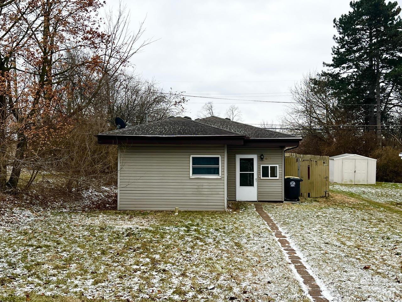Back of property featuring a shingled roof and a shed