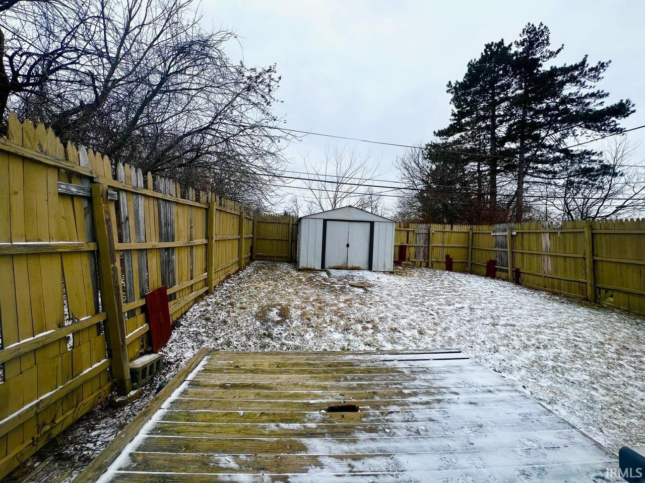 Fenced backyard featuring a shed