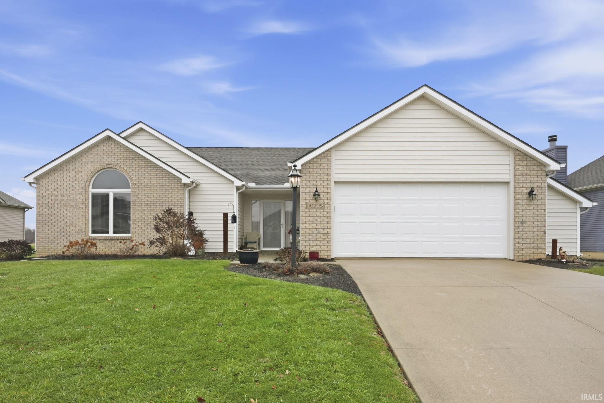 Ranch-style home featuring brick siding, concrete driveway, and a front yard