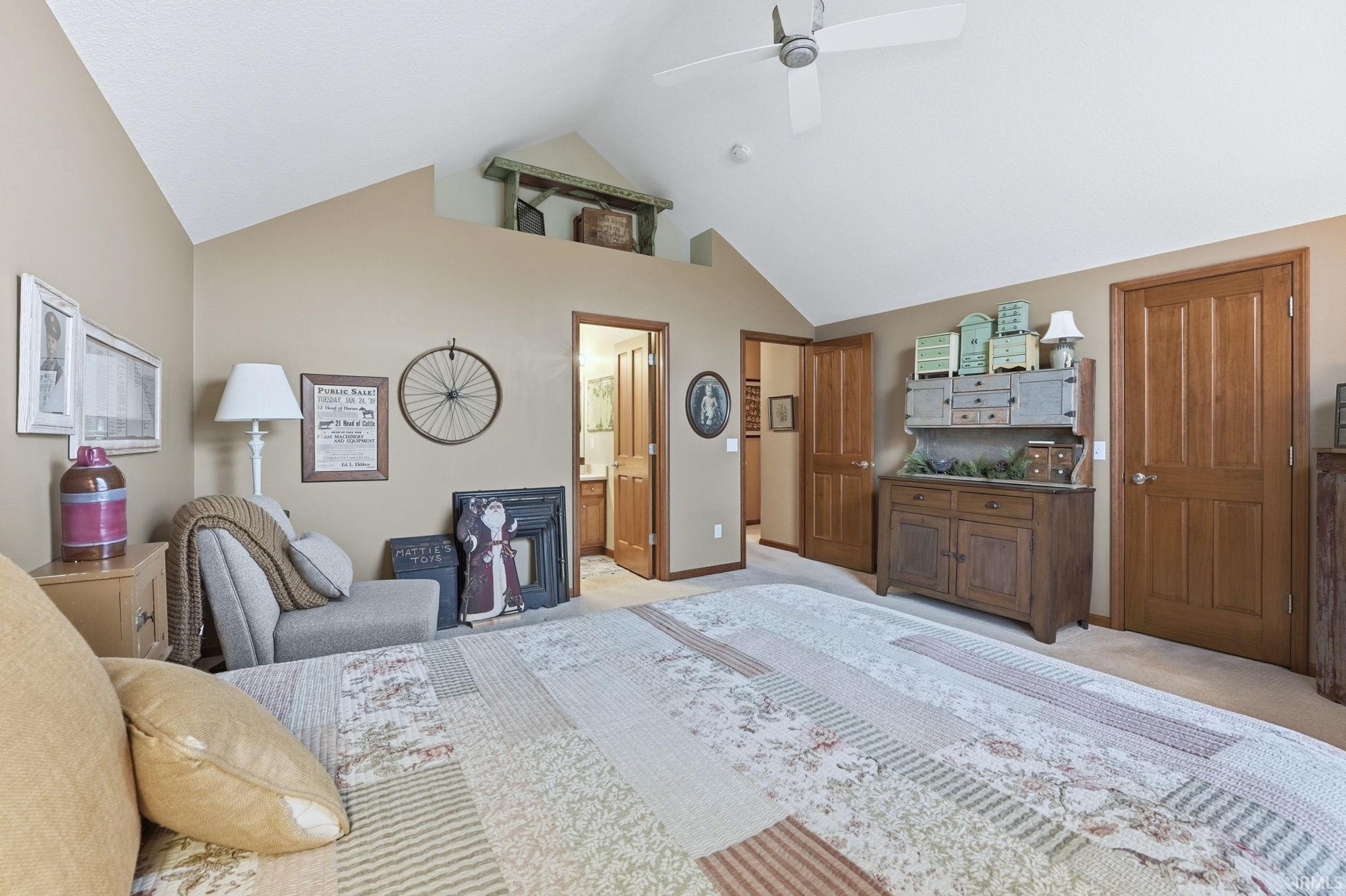 Bedroom with light carpet, ceiling fan, ensuite bathroom, and high vaulted ceiling