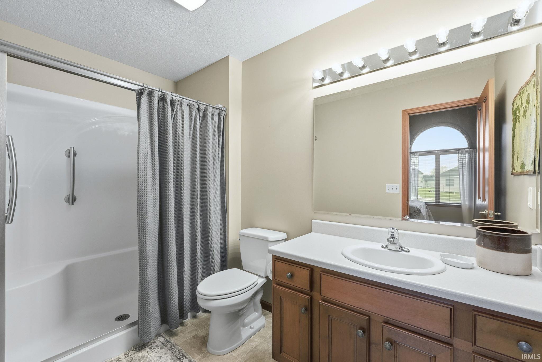 Full bathroom featuring a shower stall, vanity, and a textured ceiling