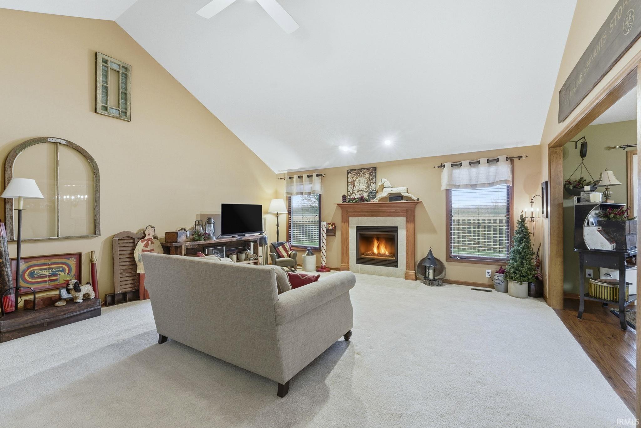 Living area with a tiled fireplace, high vaulted ceiling, and wood finished floors