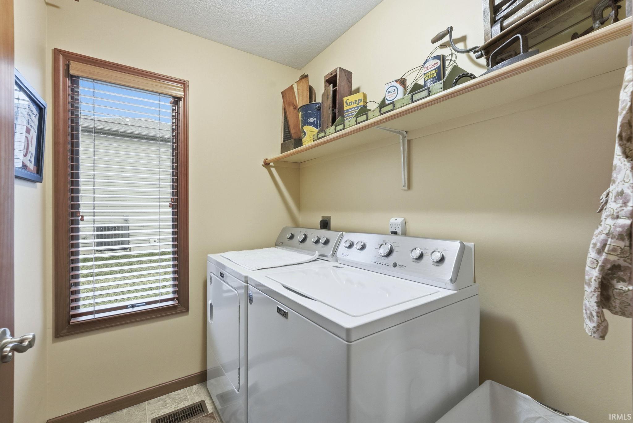 Washroom featuring healthy amount of natural light, washer and dryer, and a textured ceiling