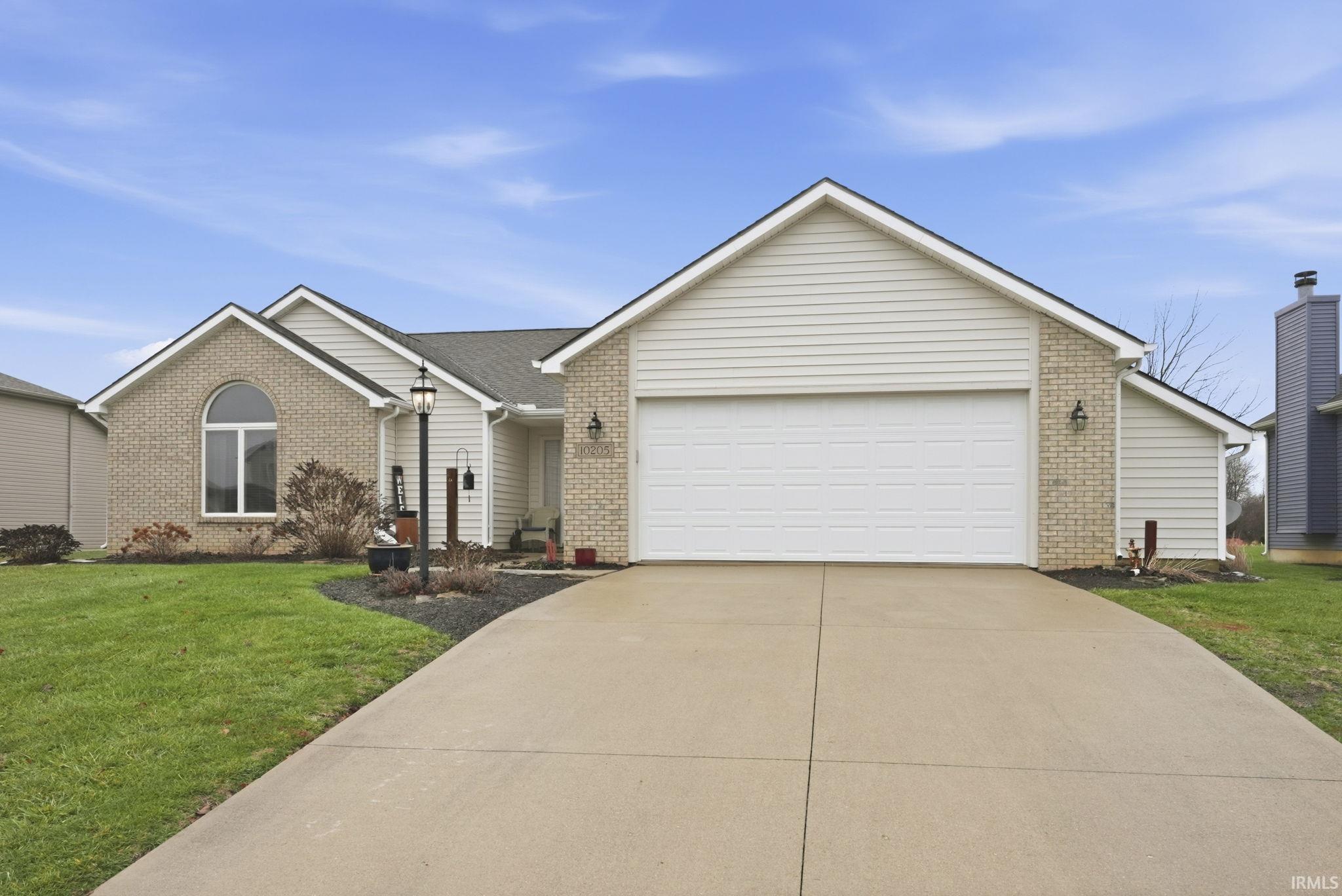 Single story home with a front yard, driveway, brick siding, and a garage