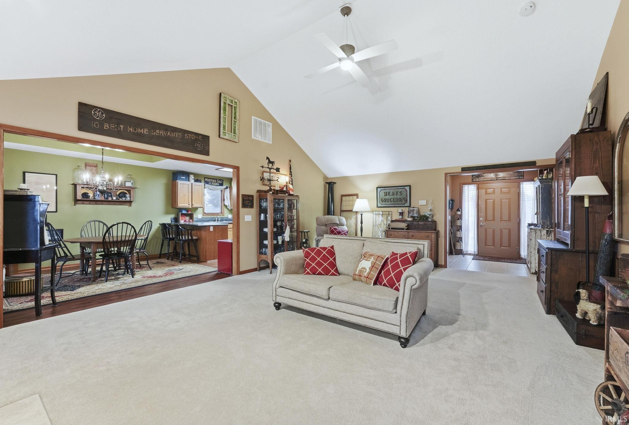 Living area featuring high vaulted ceiling, carpet floors, a ceiling fan, and a chandelier