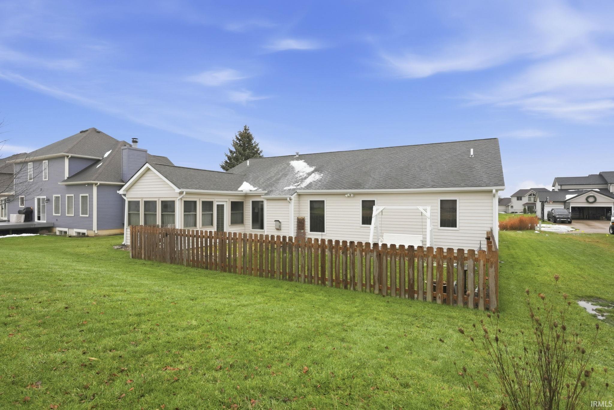 Back of house featuring a lawn and roof with shingles