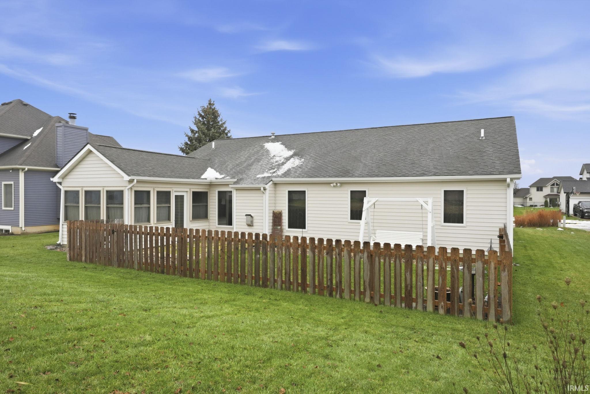 Back of house with a yard and roof with shingles