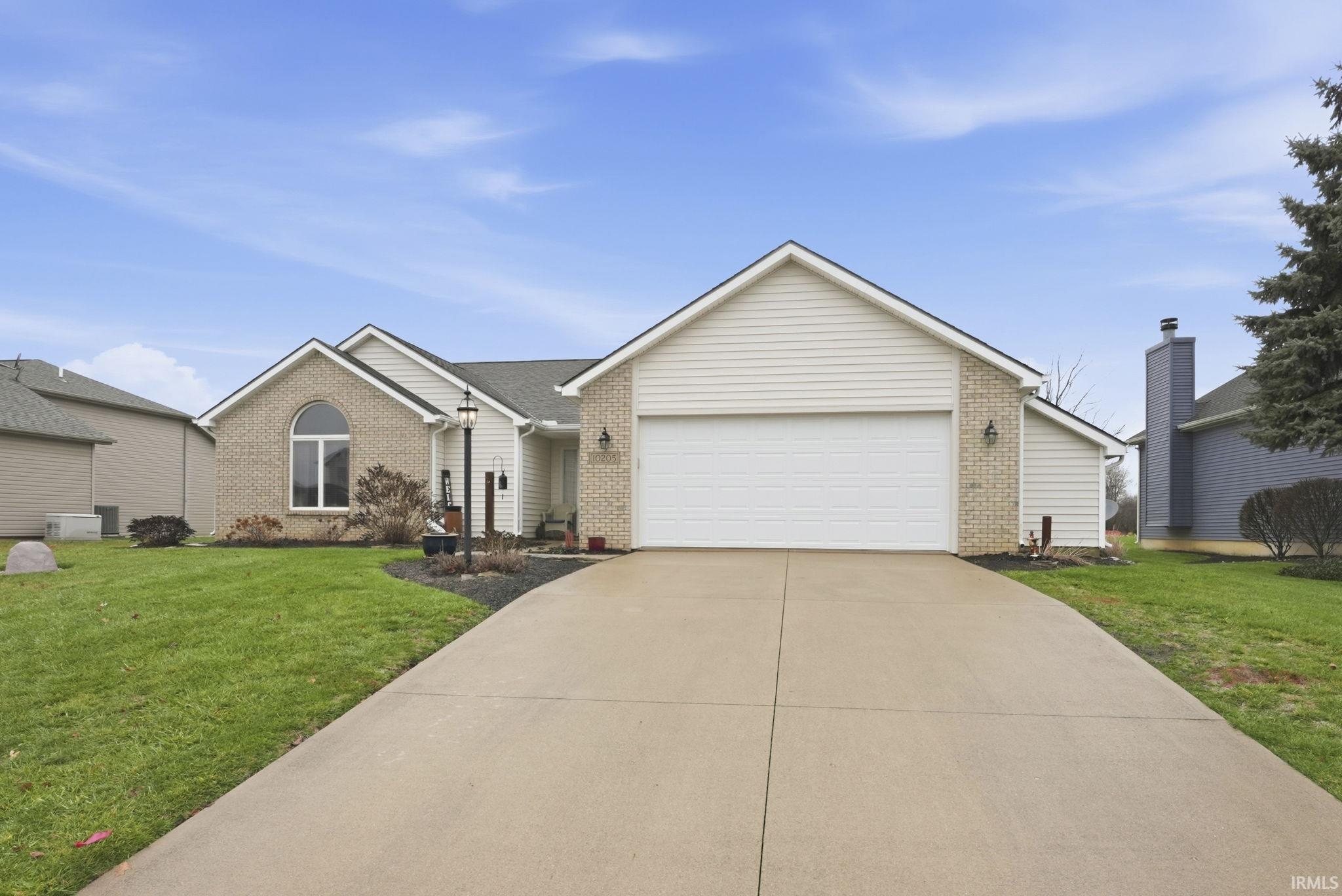Ranch-style home with a front lawn, brick siding, concrete driveway, and an attached garage