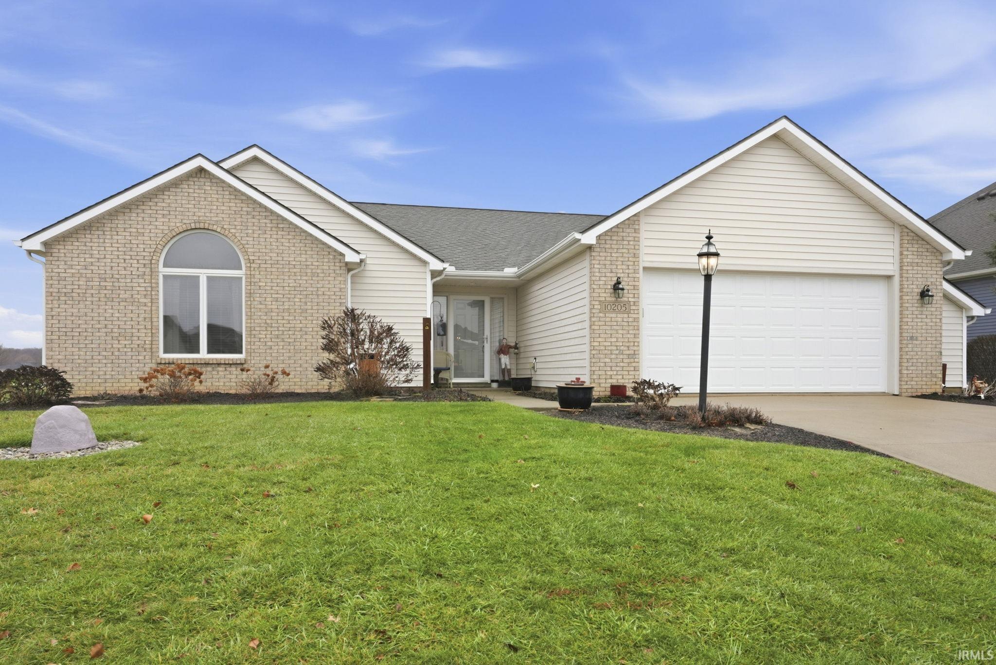 Single story home featuring concrete driveway, a front lawn, an attached garage, brick siding, and roof with shingles