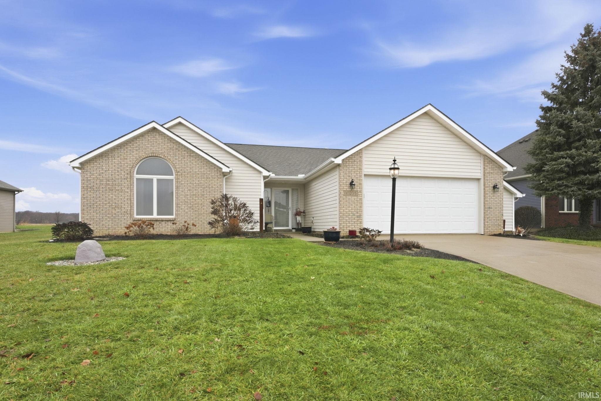 Ranch-style home with driveway, a front lawn, brick siding, an attached garage, and roof with shingles