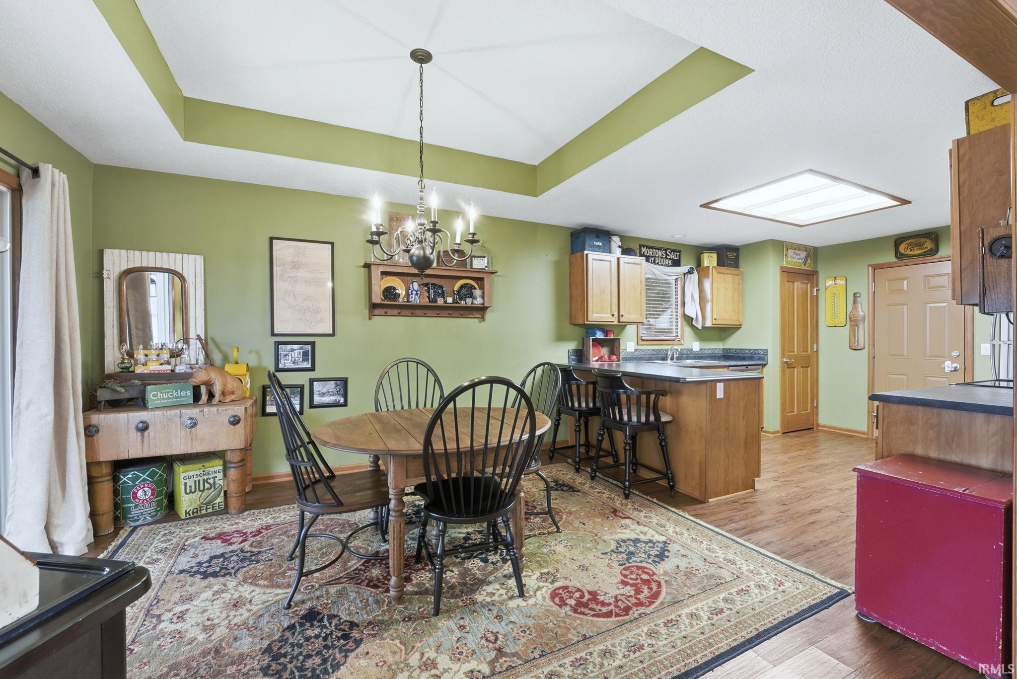 Dining area featuring a tray ceiling, a chandelier, and wood finished floors