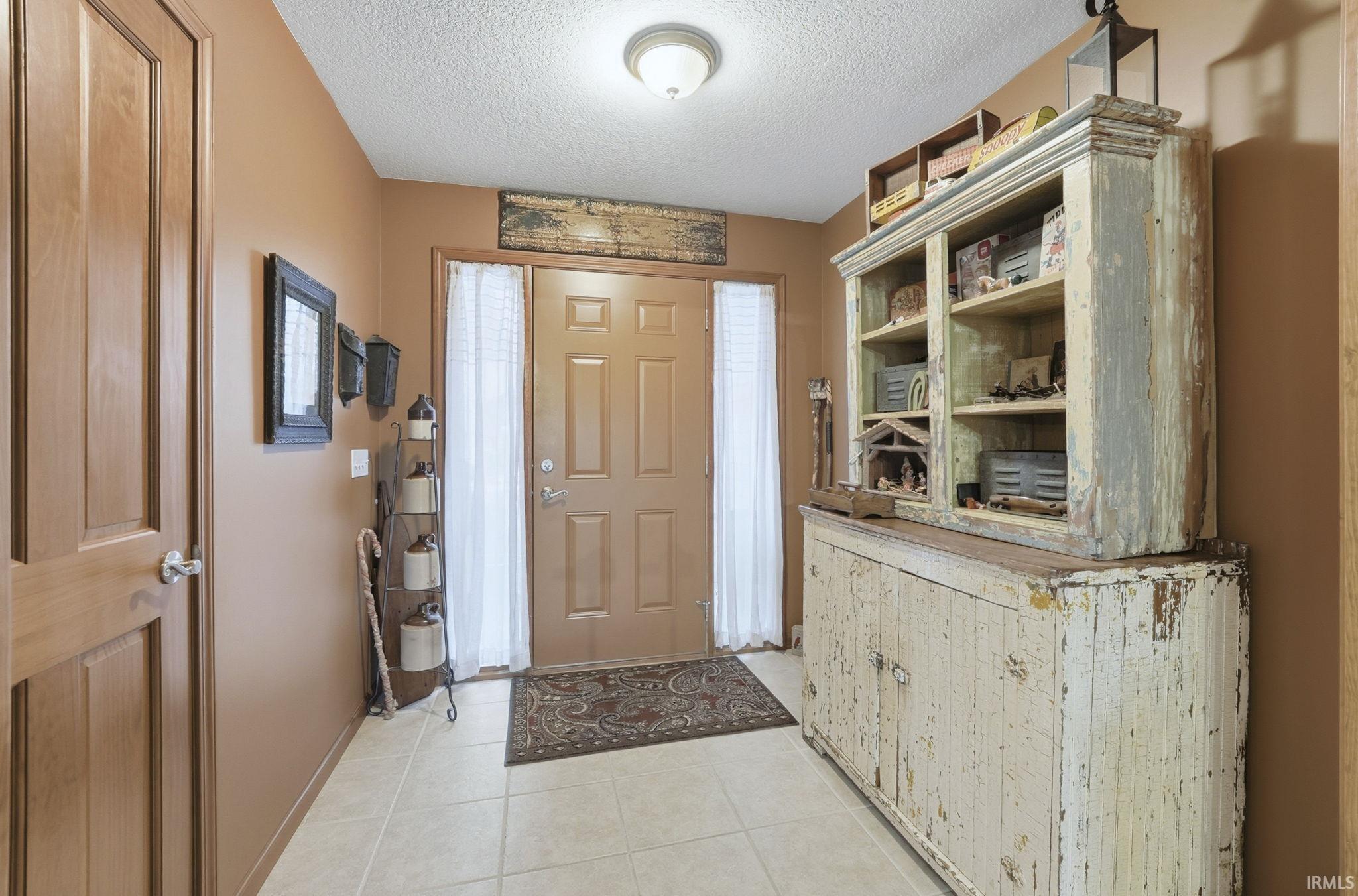 Foyer featuring a textured ceiling and light tile patterned floors