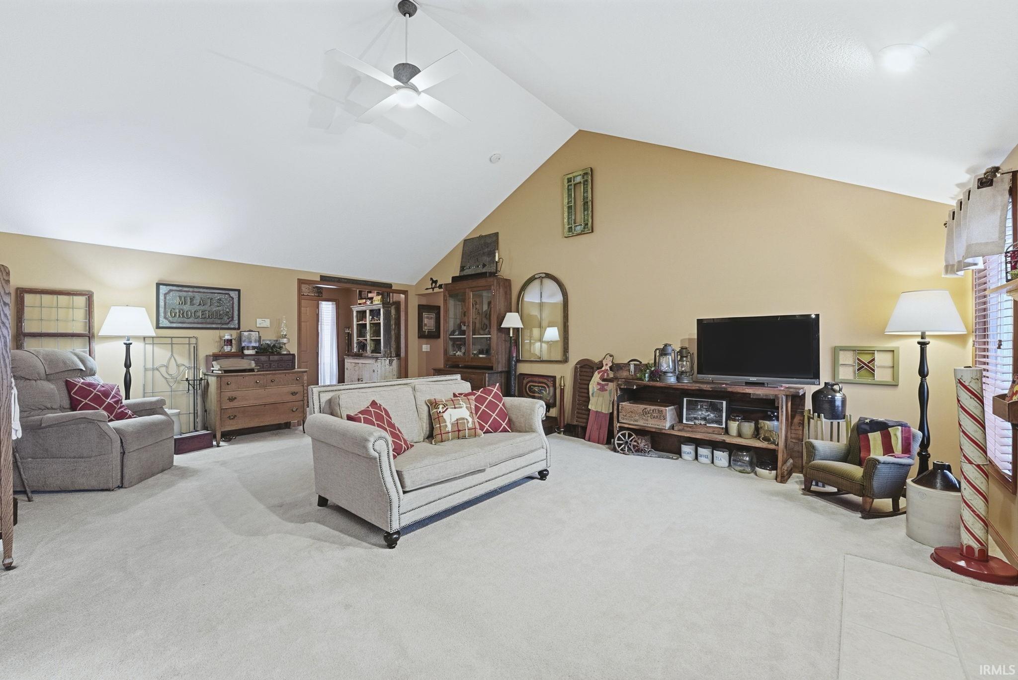 Living room featuring a ceiling fan, carpet floors, and high vaulted ceiling