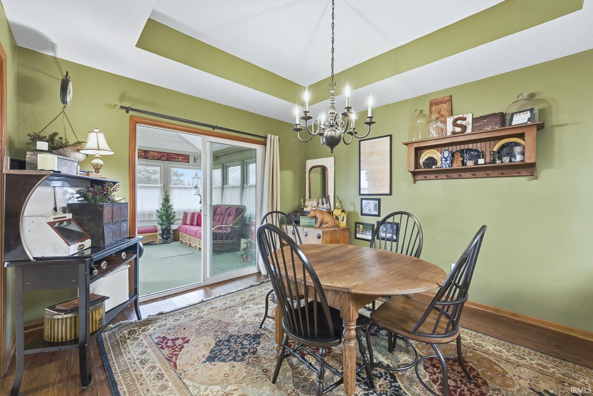 Dining room with a raised ceiling, a chandelier, and wood finished floors