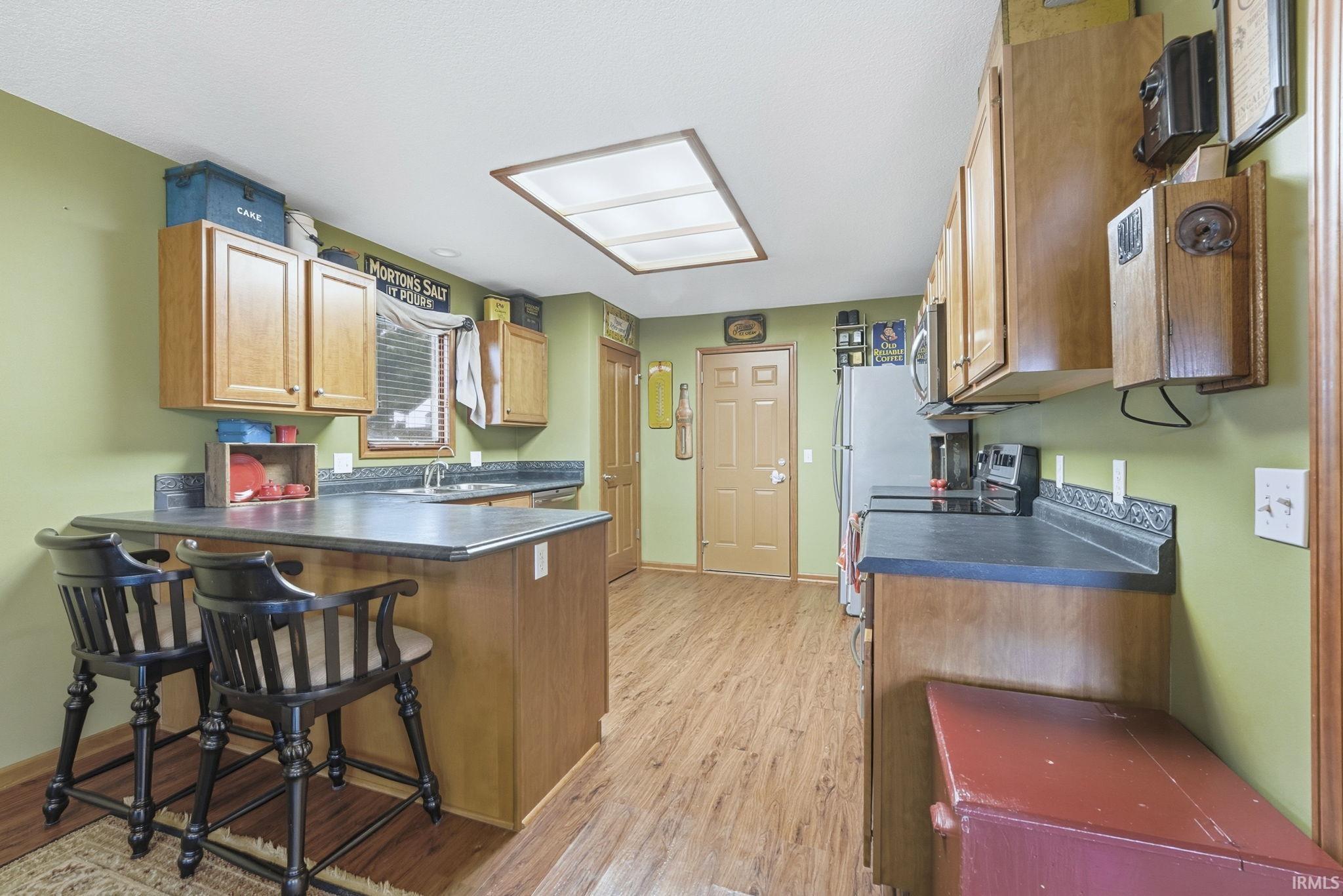 Kitchen featuring dark countertops, a peninsula, brown cabinets, and a kitchen breakfast bar