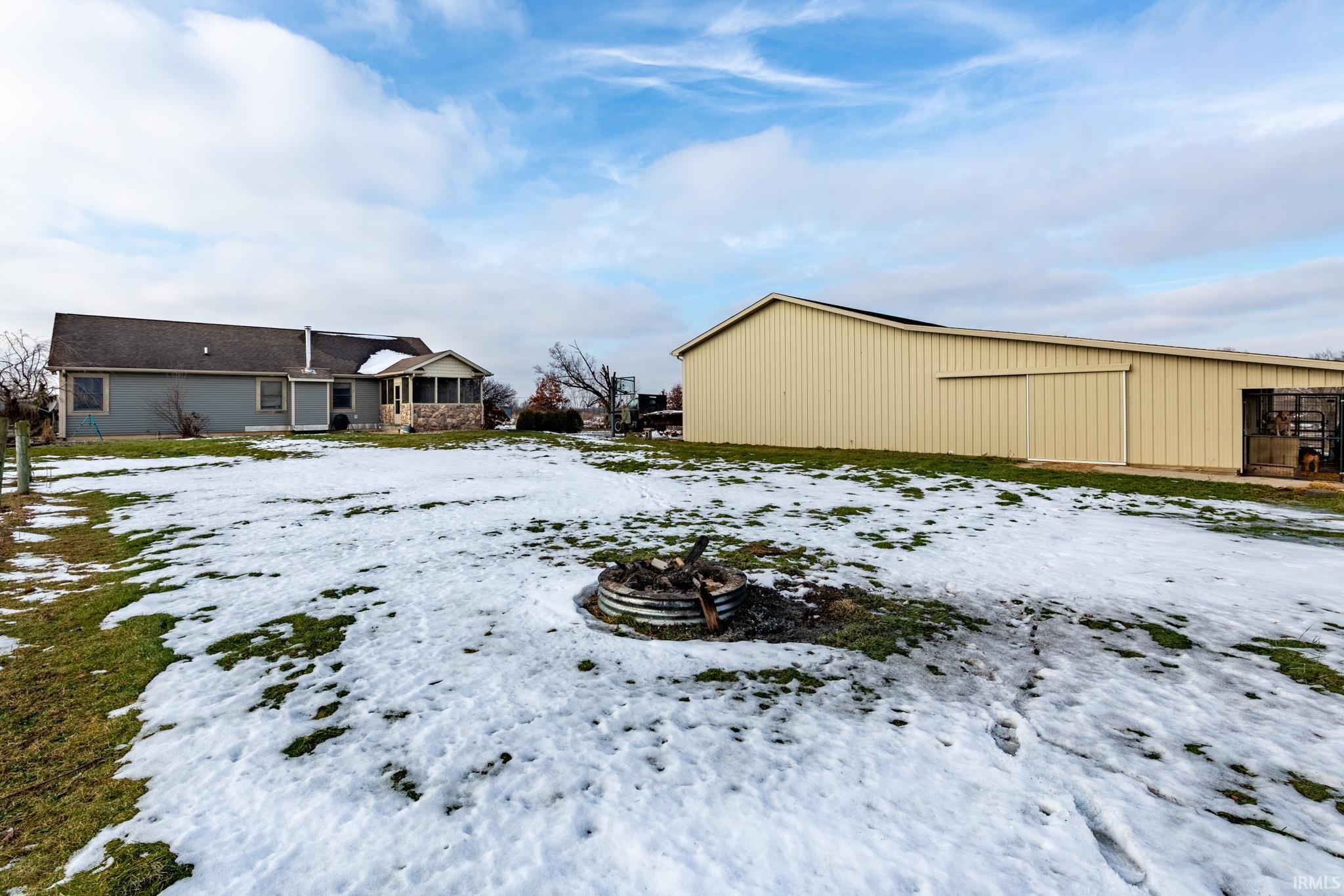 Snowy yard featuring a pole building and an outbuilding