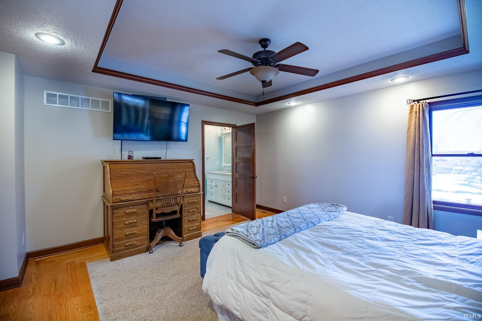 Bedroom featuring a tray ceiling, recessed lighting, ceiling fan, wood finished floors, and a desk