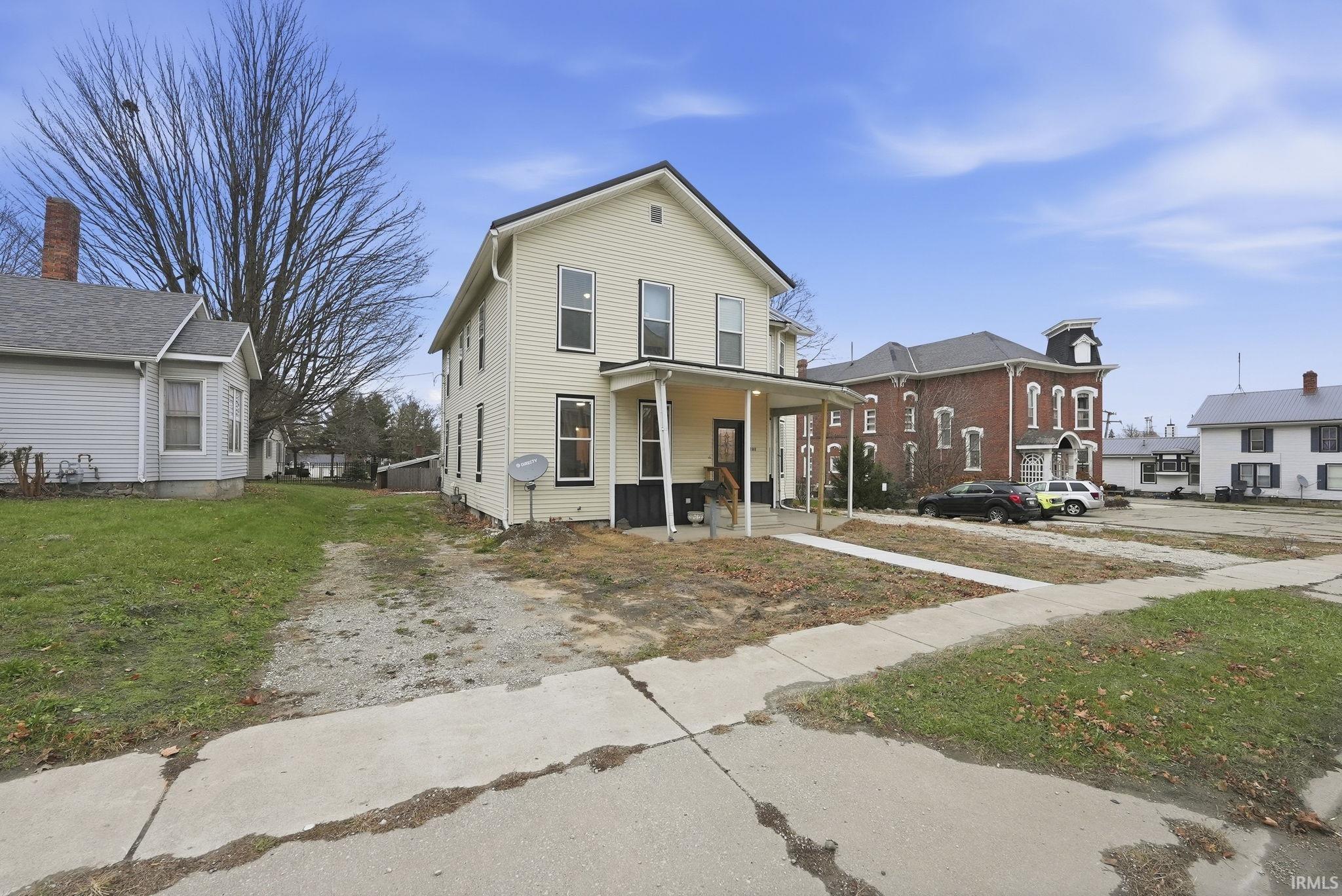 View of front of home with a porch, a front yard, a residential view, and driveway