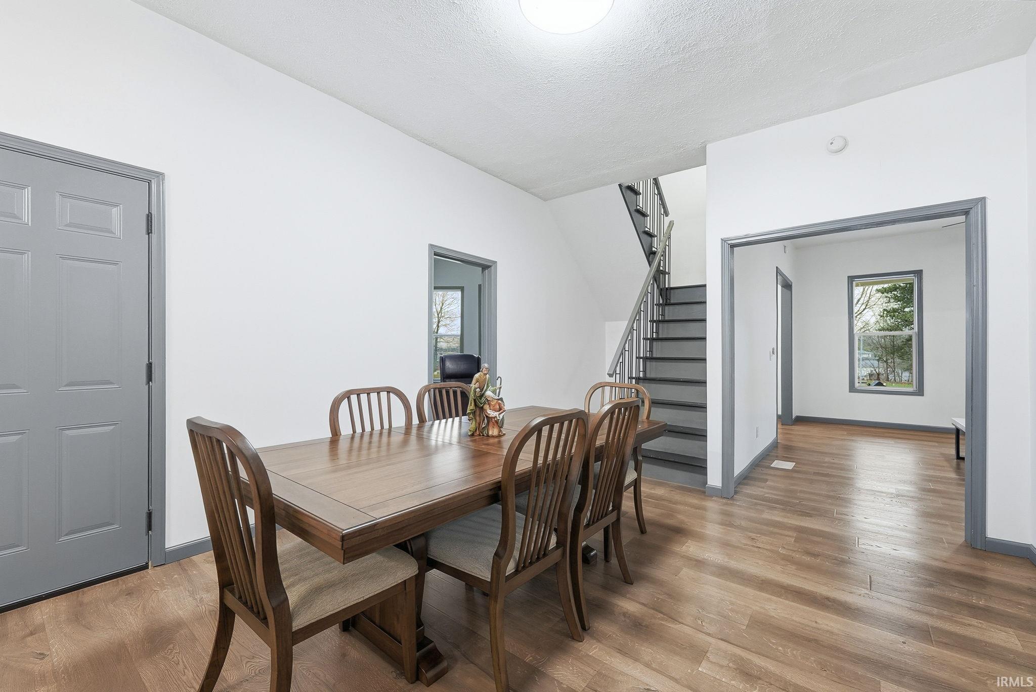 Dining space featuring stairway, light wood-type flooring, and a textured ceiling