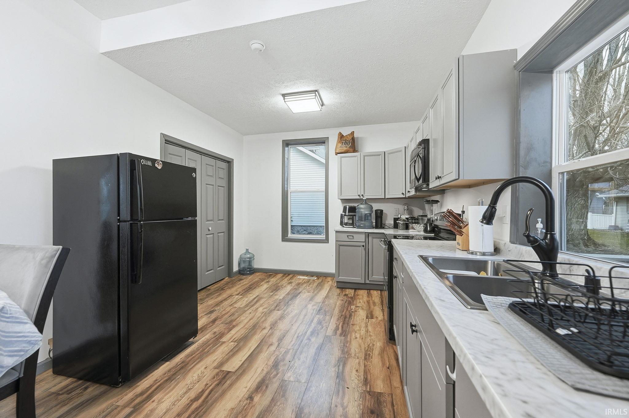 Kitchen featuring black appliances, gray cabinets, light wood-style flooring, and a textured ceiling