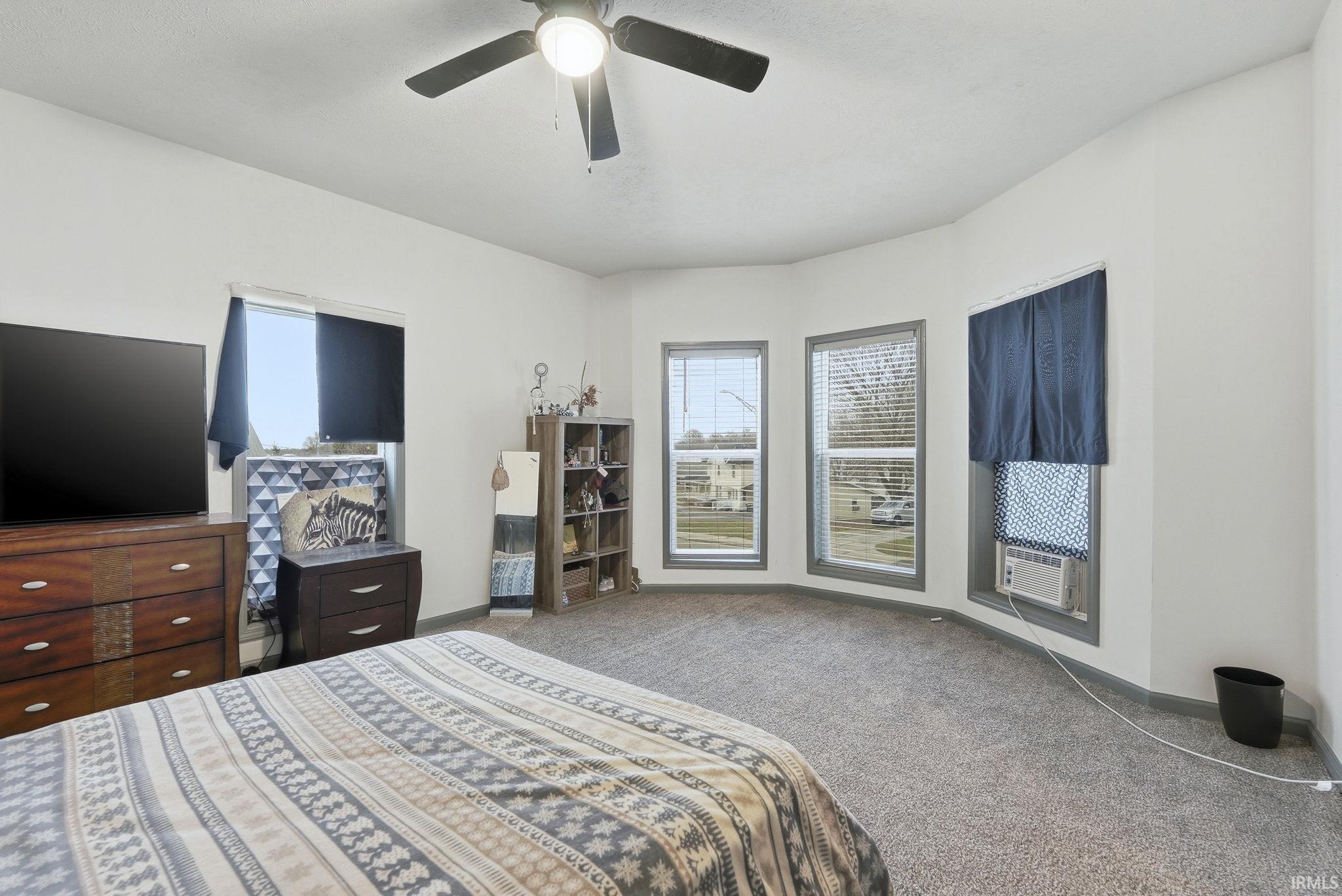 Carpeted bedroom with a ceiling fan and baseboards
