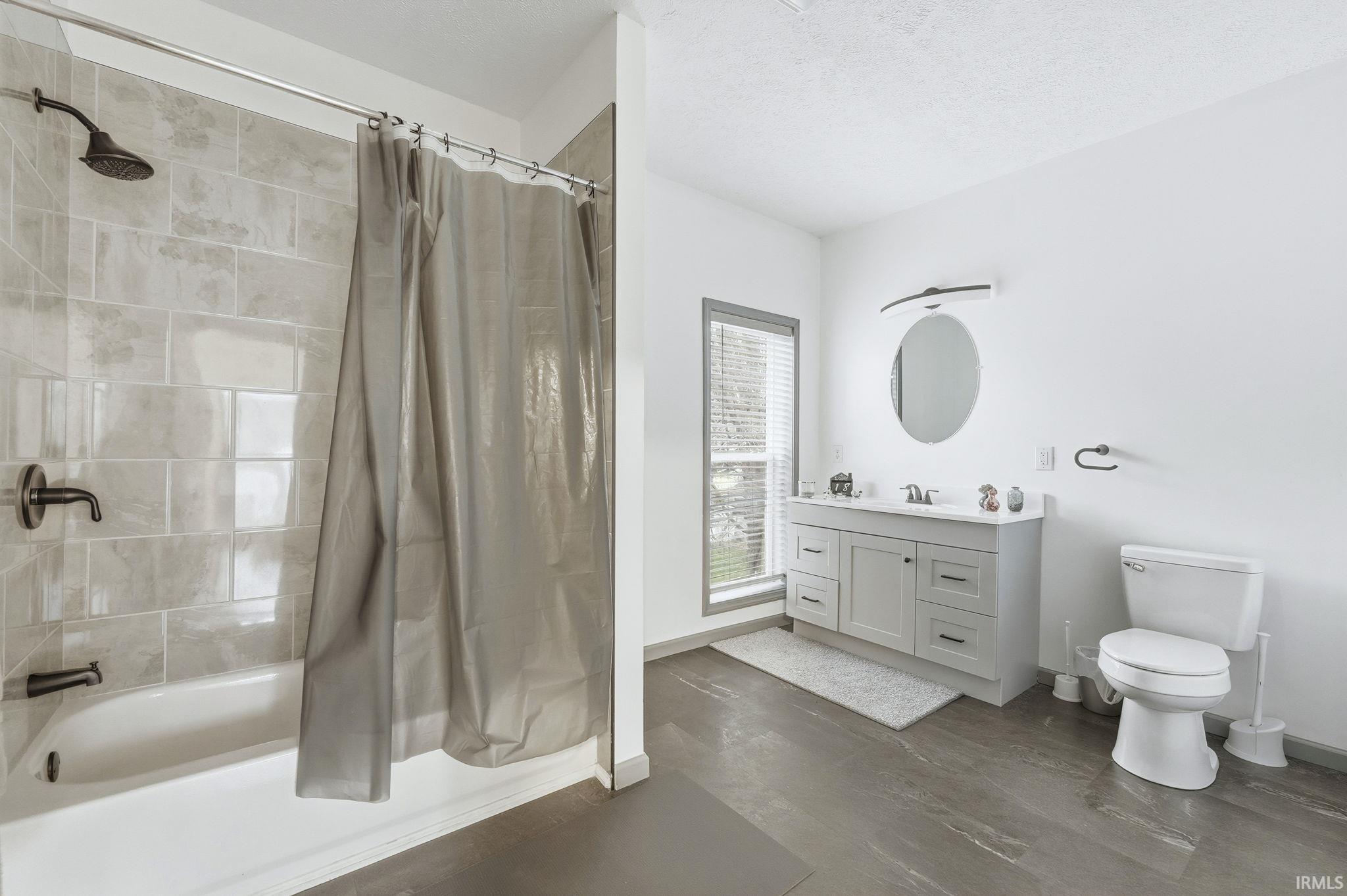Bathroom with shower / bath combo with shower curtain, vanity, and a textured ceiling