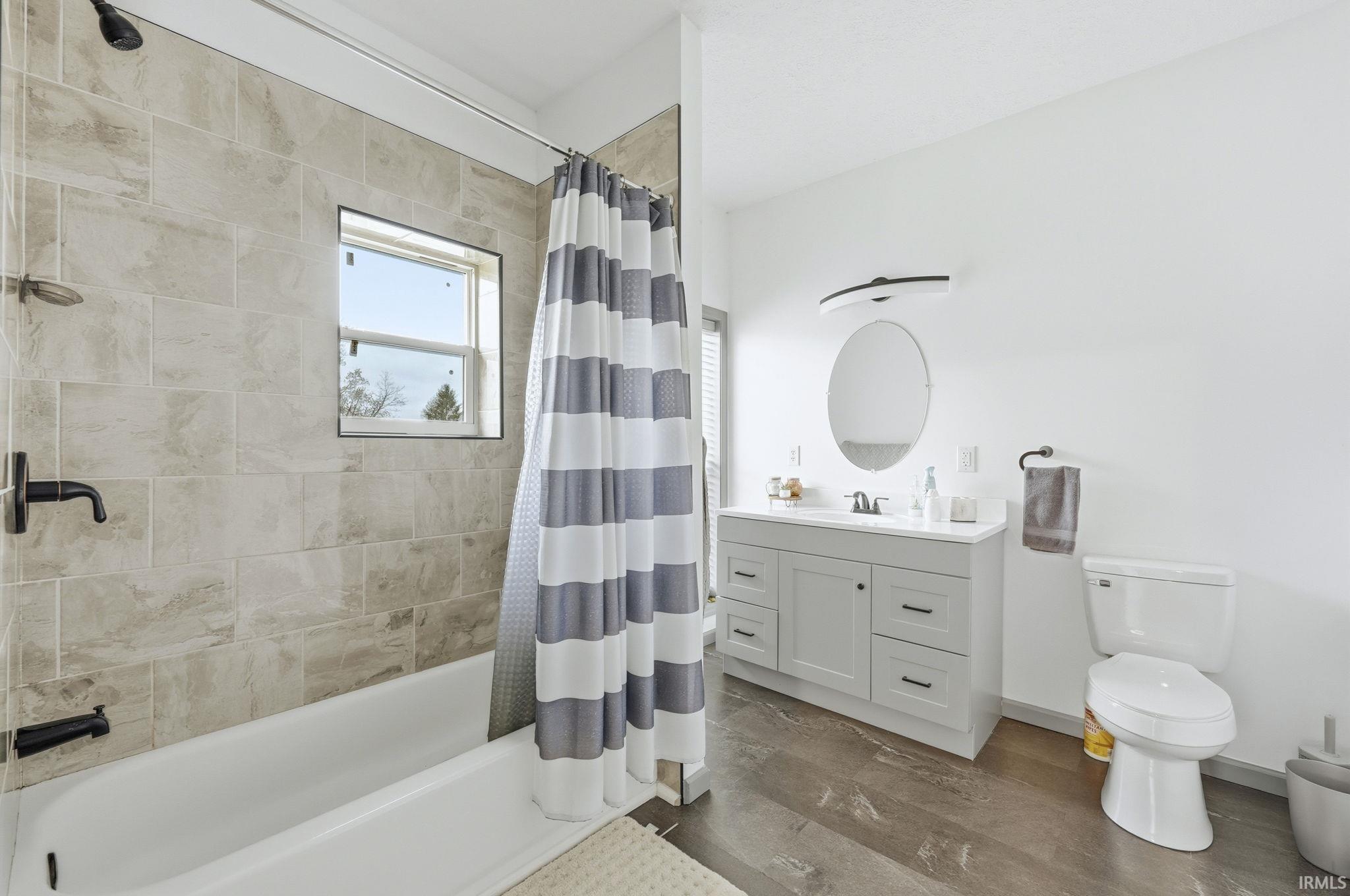 Full bath with vanity, shower / bath combo with shower curtain, and dark wood finished floors