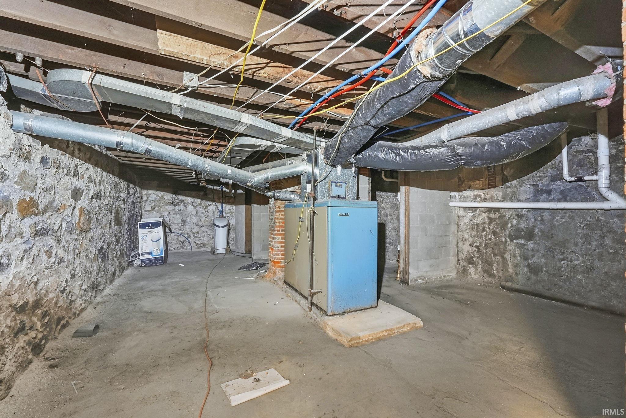Unfinished below grade area featuring heating unit and a water softener system