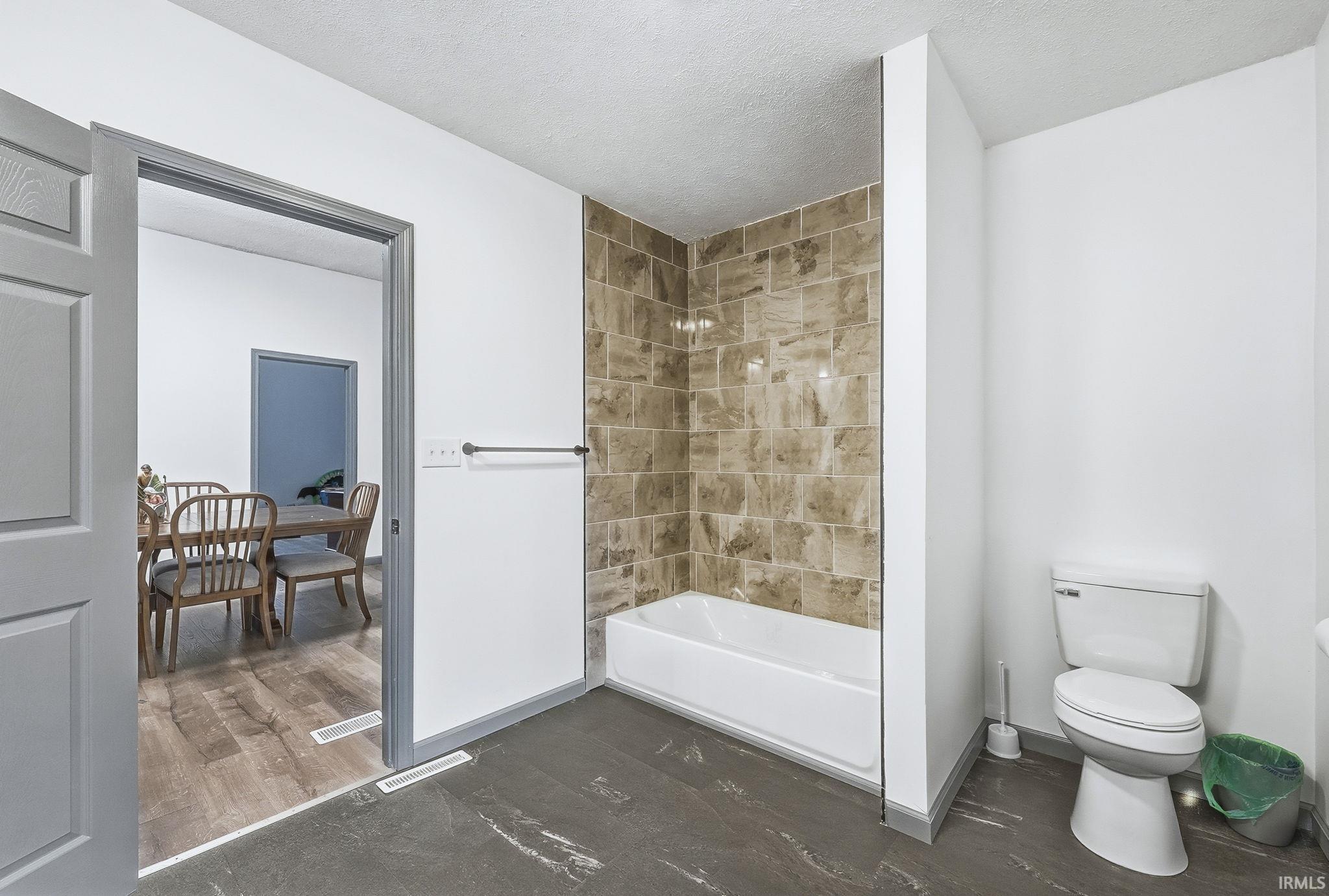 Bathroom featuring  shower combination and a textured ceiling