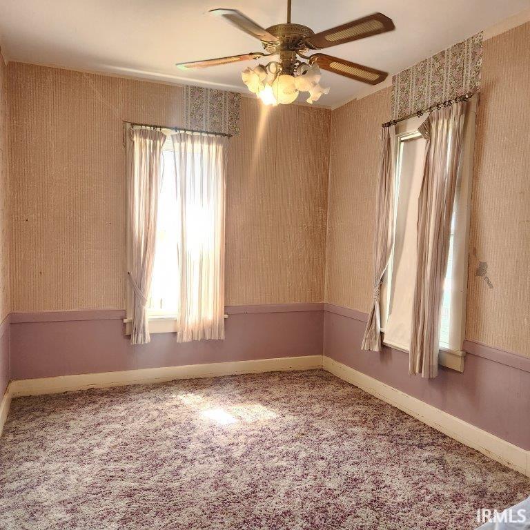 Carpeted empty room with wallpapered walls and ceiling fan
