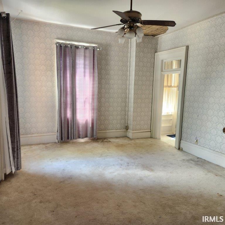 Unfurnished room with wallpapered walls, ceiling fan, and carpet floors