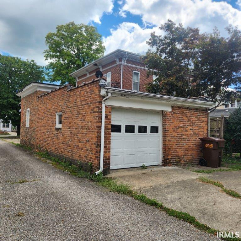View of home's exterior with brick siding, a garage, and driveway
