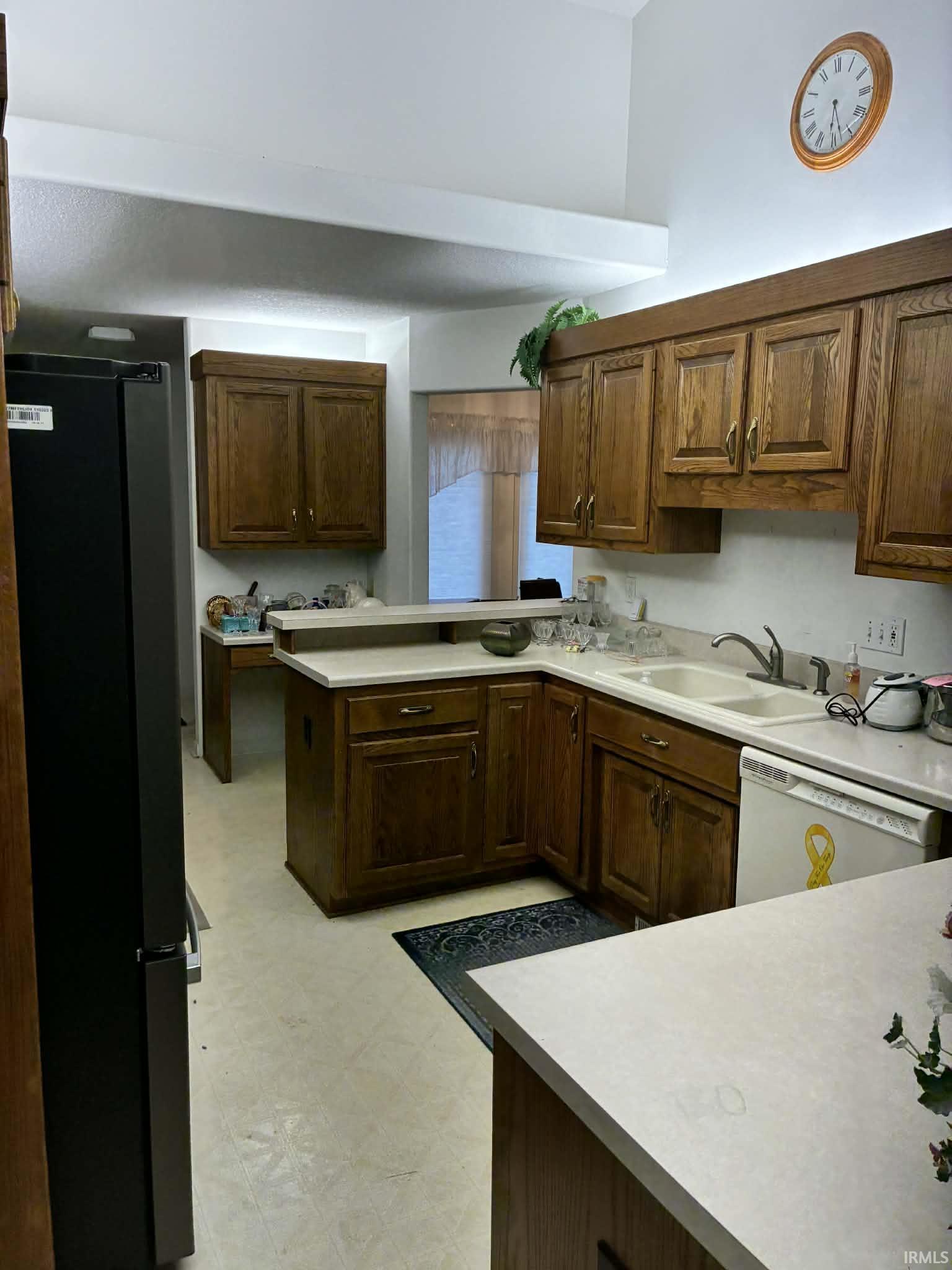 Kitchen with light flooring, freestanding refrigerator, white dishwasher, and light countertops