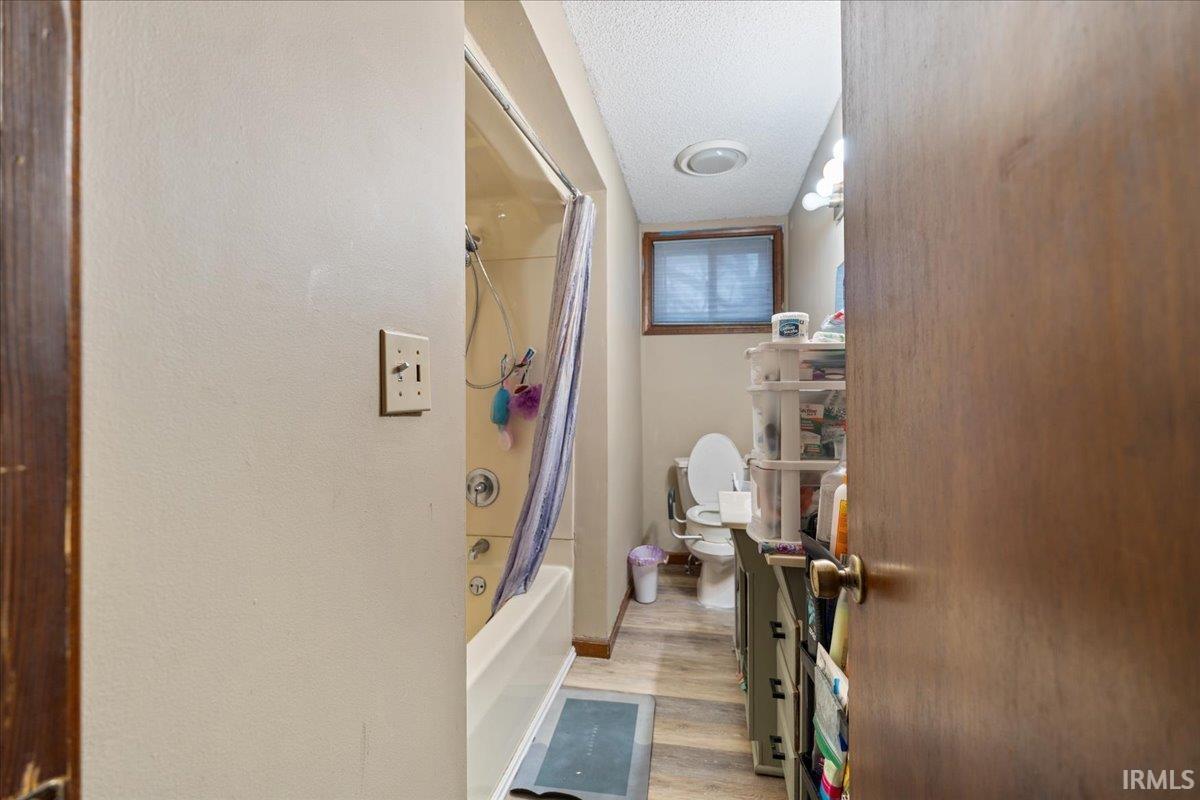 Full bath featuring shower / tub combo, a textured ceiling, light wood-type flooring, and vanity
