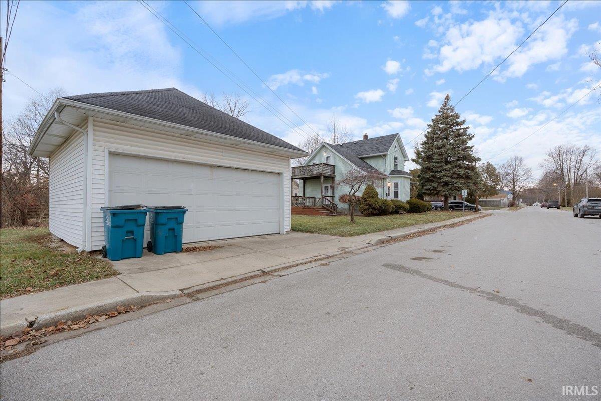 View of property exterior featuring a garage, an outdoor structure, and a residential view