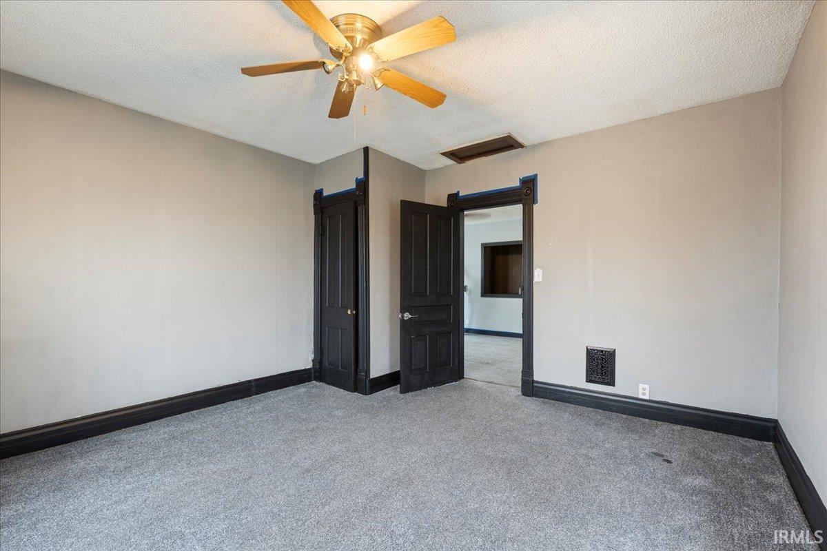 Unfurnished room featuring attic access, a textured ceiling, carpet floors, and a ceiling fan
