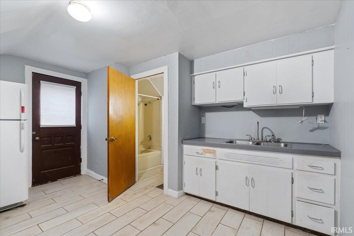 Kitchen featuring freestanding refrigerator, white cabinetry, and wood tiled floors