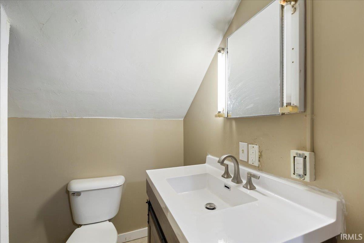 Half bathroom with lofted ceiling and vanity