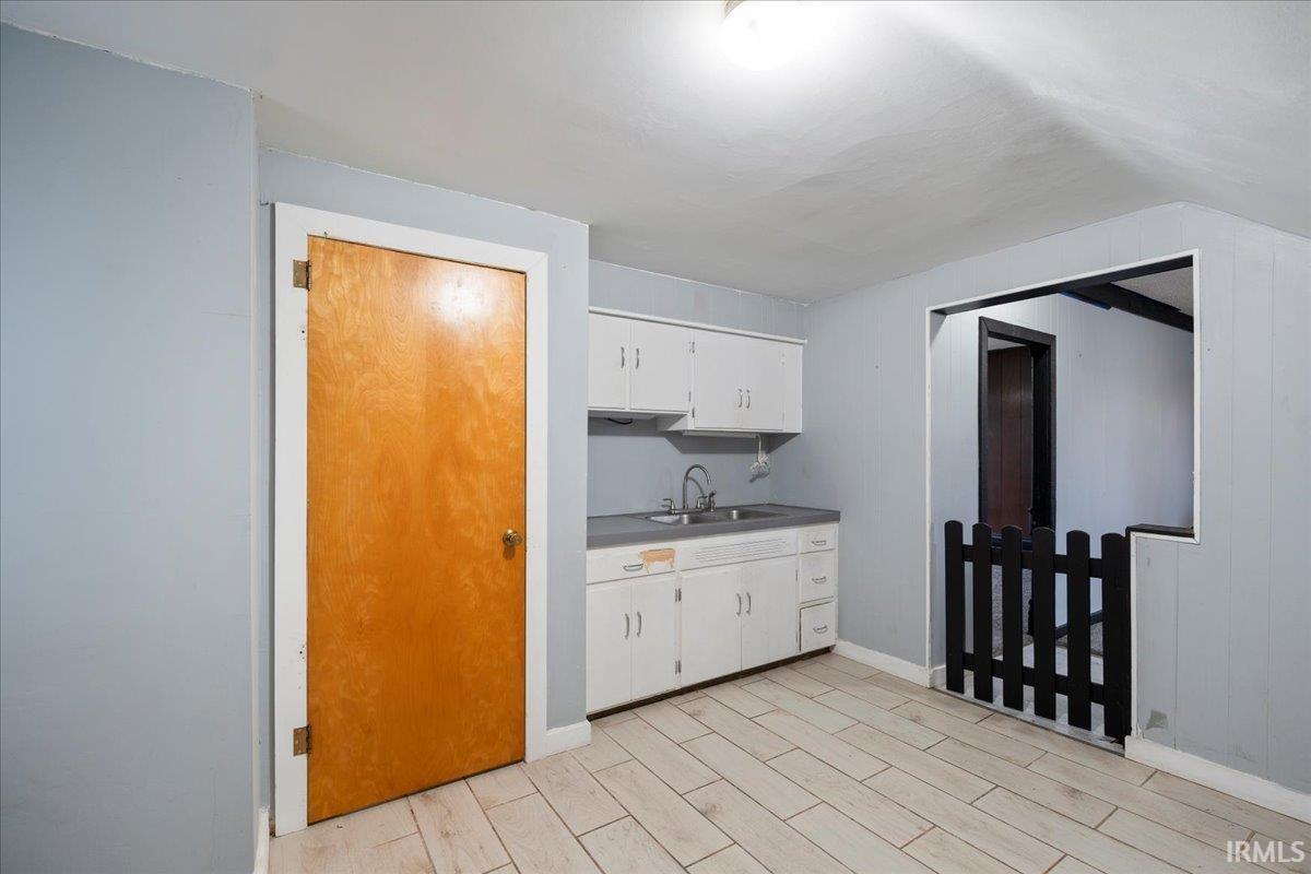 Bar featuring white cabinetry, wood finish floors, and light countertops