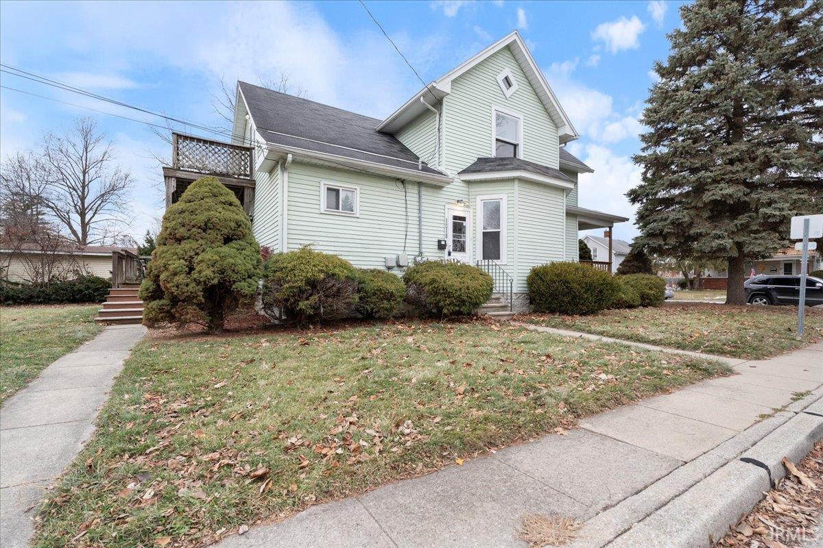 View of front of home with a front lawn, a shingled roof, and a balcony