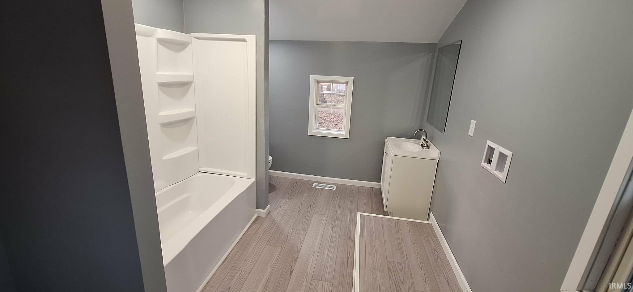 Bathroom featuring vanity, light wood-style flooring, and  shower combination