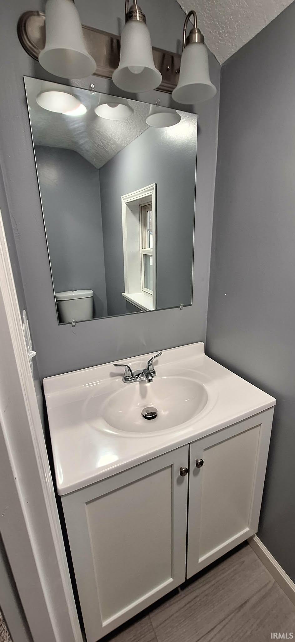 Bathroom featuring vanity, a textured ceiling, and dark wood-style flooring