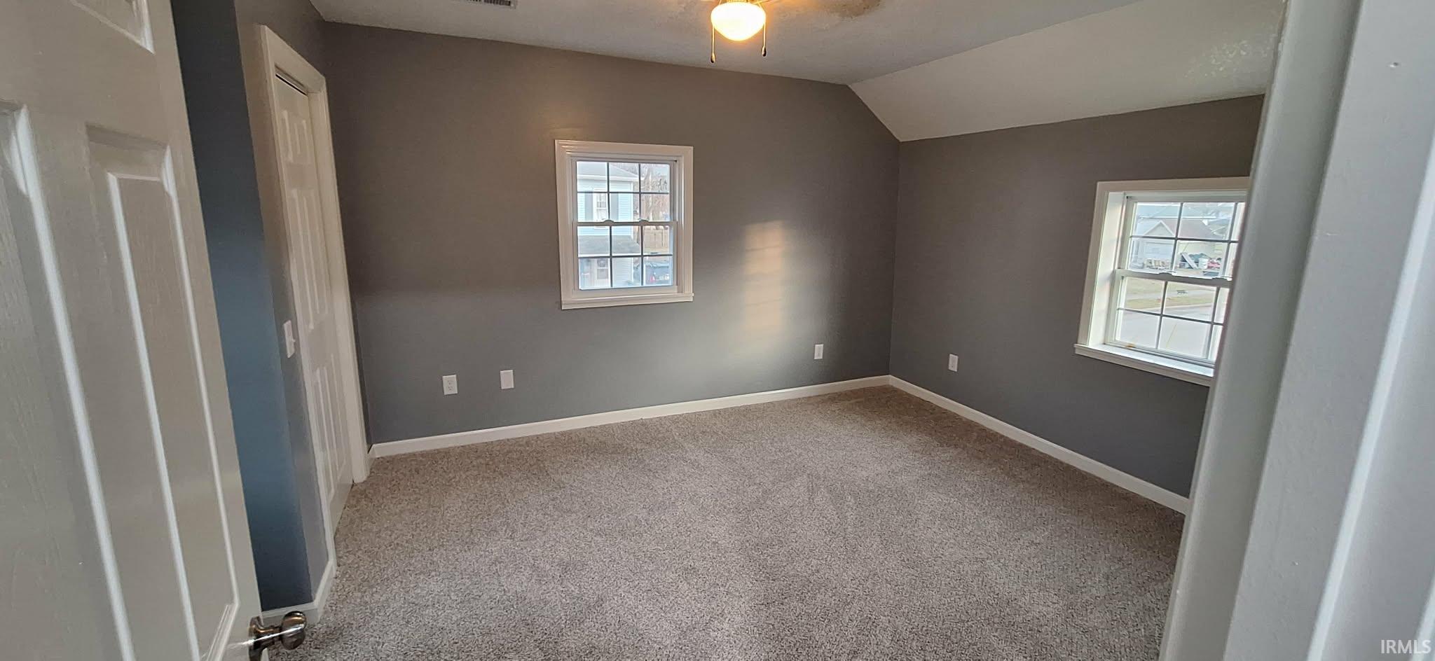 Unfurnished room featuring lofted ceiling and light carpet